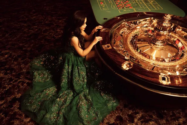 Một người phụ nữ quyến rũ cầm chip casino trong không gian ánh đèn rực rỡ, đại diện cho bầu không khí casino trực tuyến của QWE123.